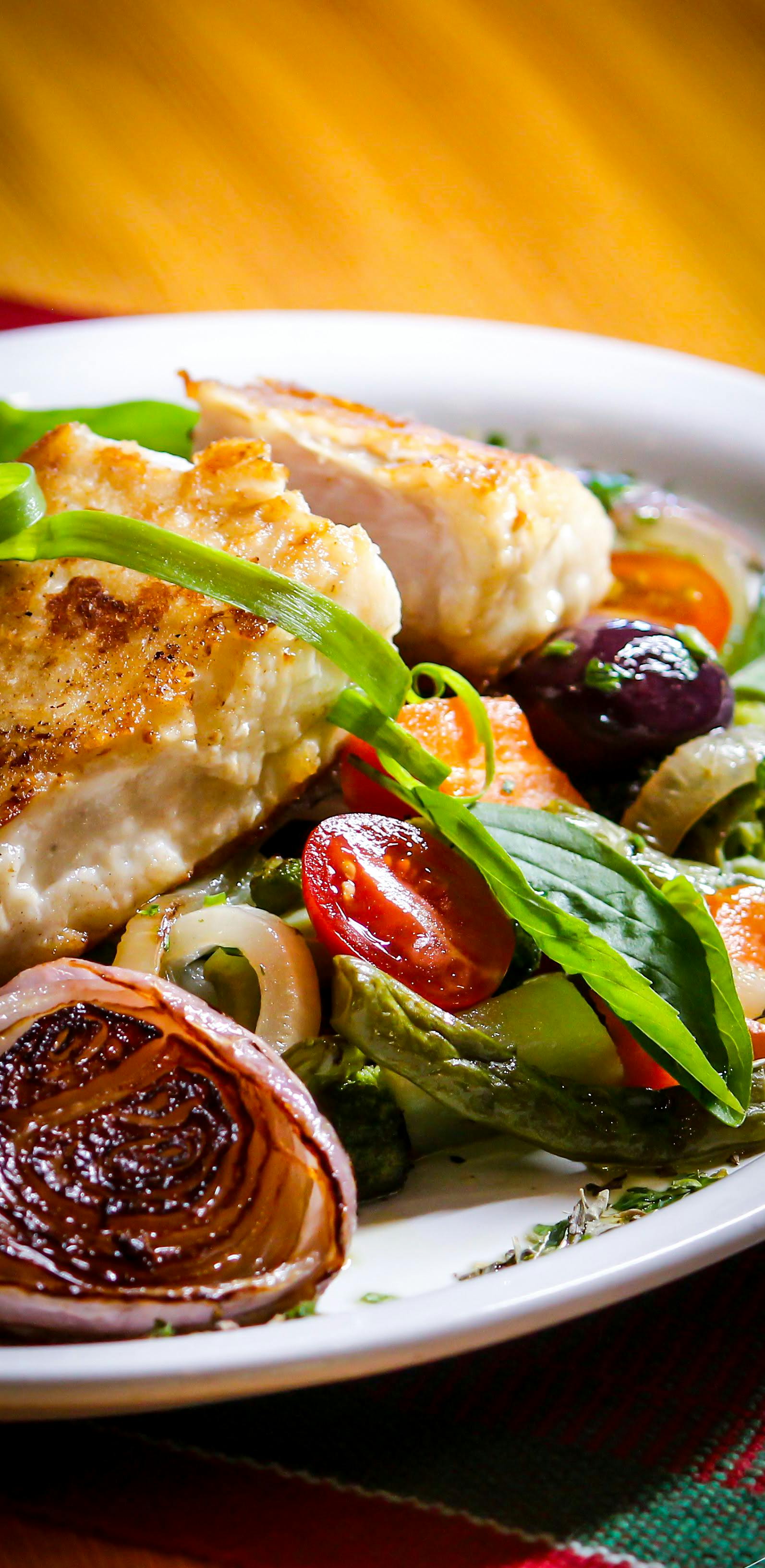Grilled chicken over fresh salad with vegetables and herbs