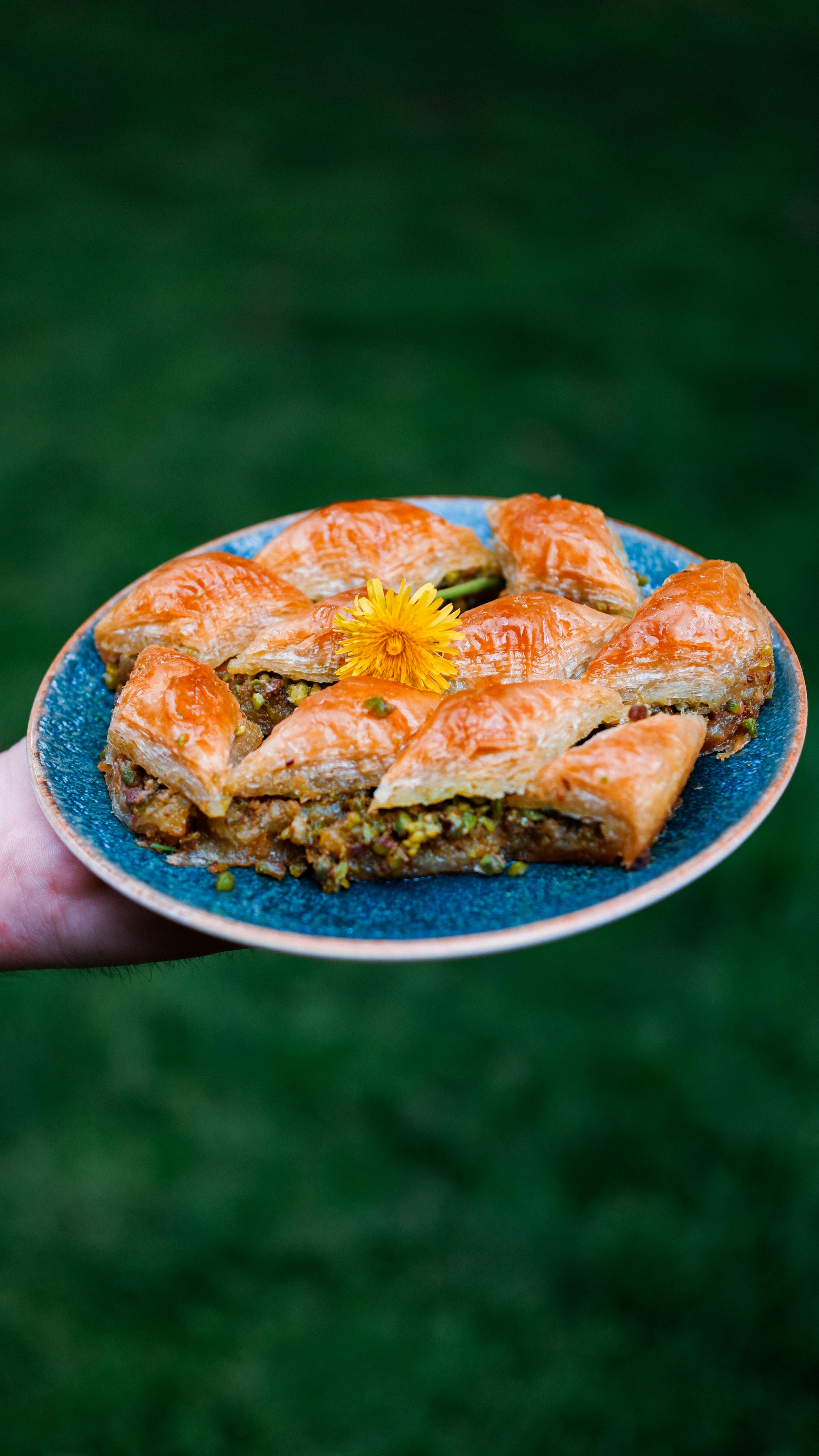 Round baklava on a blue plate with a dandelion flower