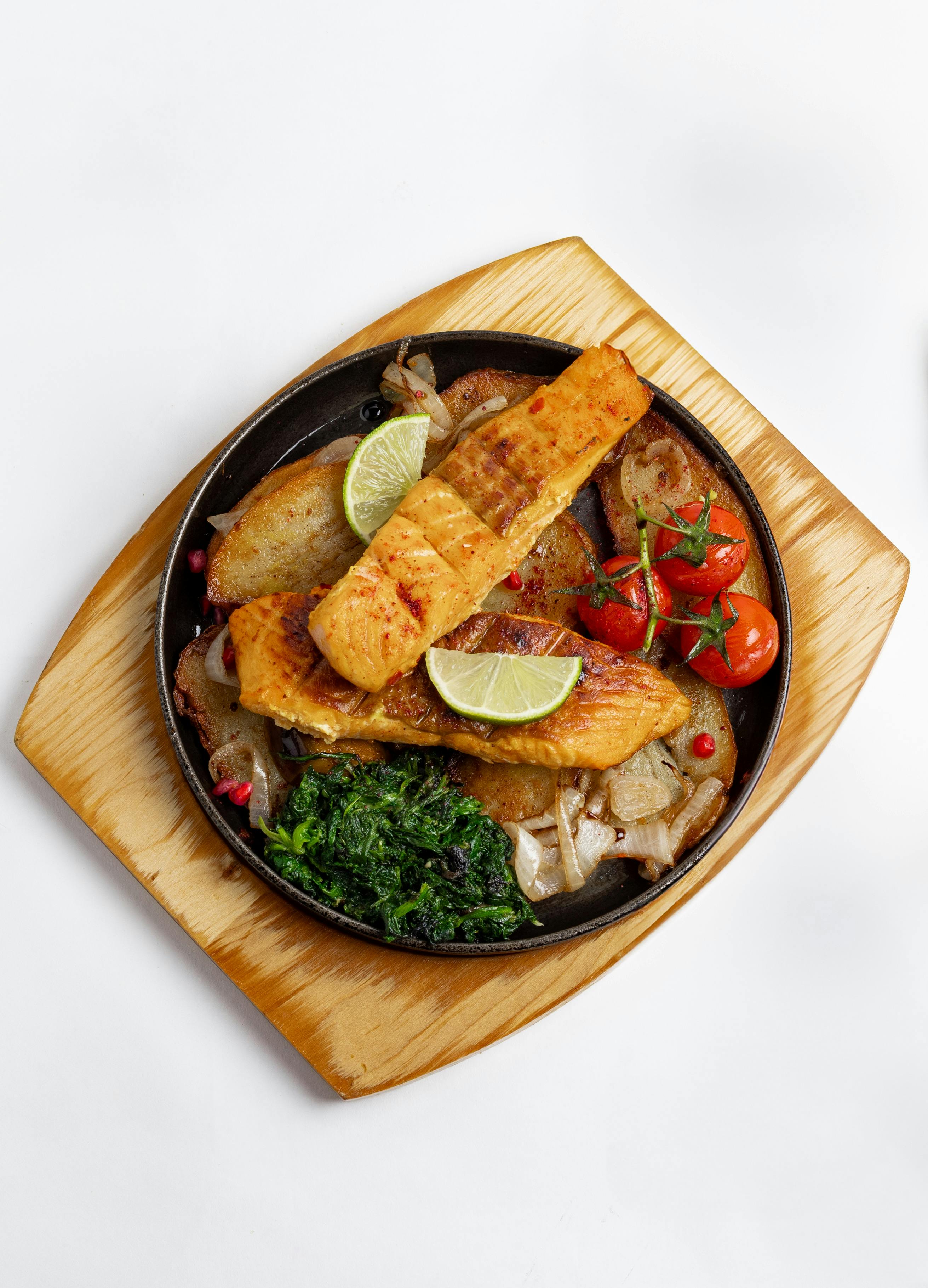 Salmon fillet in cast iron skillet with spinach and cherry tomatoes