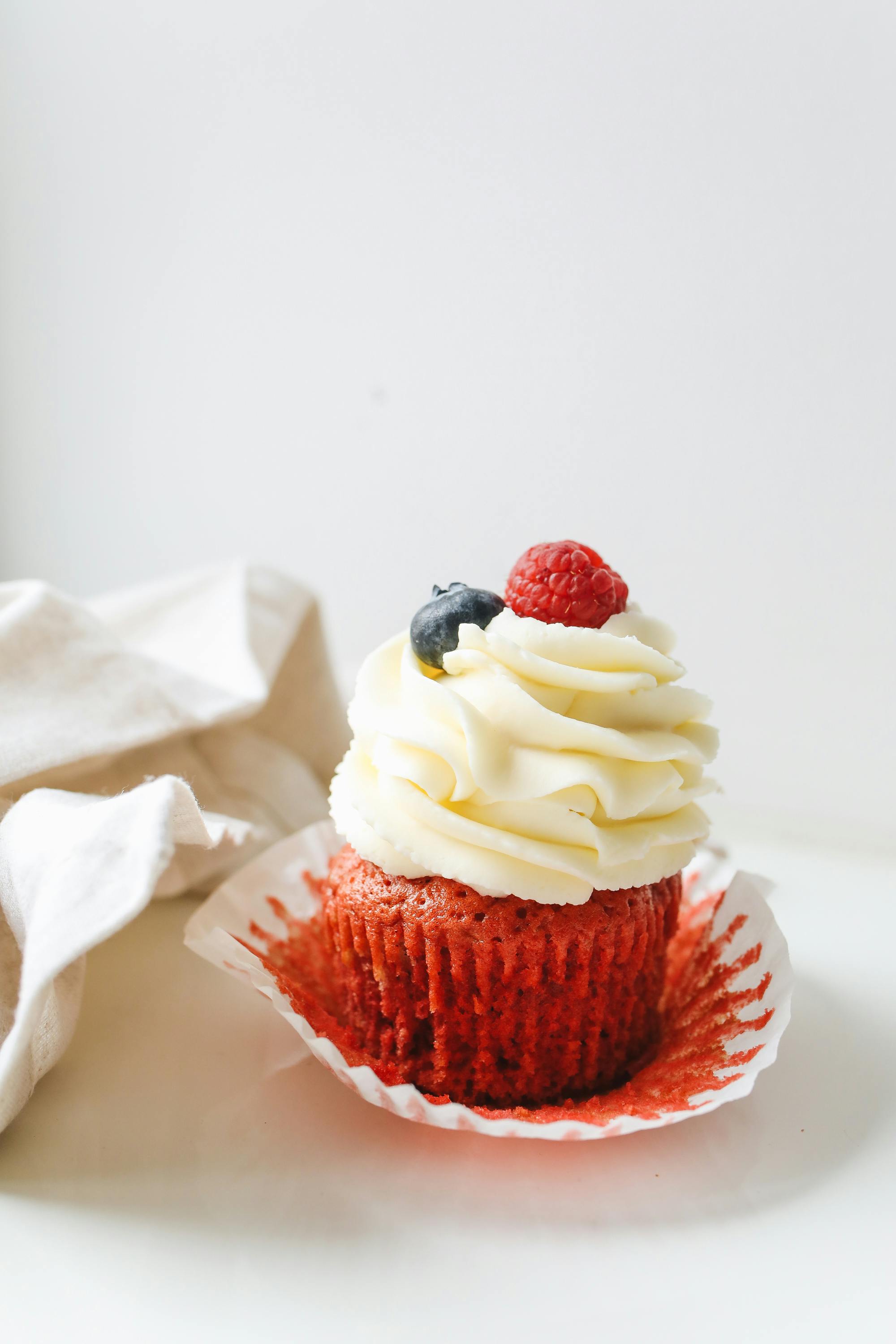 Red velvet cupcake with cream cheese frosting and berries
